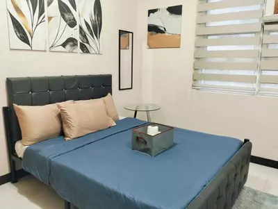 a bedroom with a bed with a blue blanket and a table at #Affordable Condotel Newport Boulevard in Manila