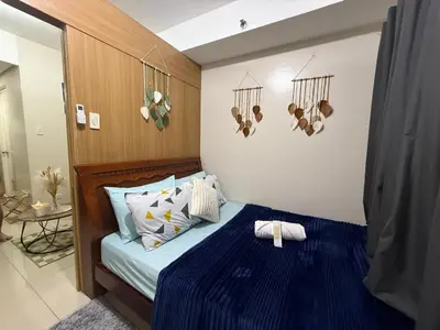 a bedroom with a bed with a blue comforter at Shell and Shorline Bliss Manila Staycation in Manila