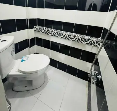 a bathroom with a toilet and black and white tiles at T&A Building in Manila
