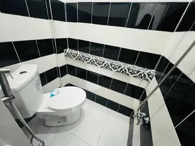 a bathroom with a toilet and black and white tiles at T&A Building in Manila