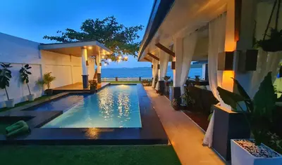 a swimming pool in front of a house with the ocean at OYO 1175 Casa Ana in Manila