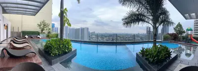 a large swimming pool with a view of a city at Tahanan Studio at Salcedo Skysuites in Manila