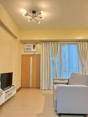 a living room with a couch and a television at Big Studio Condo Across Manila Airport NAIA T3 WITH WIFI in Manila
