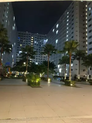 a city square with palm trees and buildings at night at Condo MOA Complex Pasay - Shore 1 Tower C2 Residence - Home away from Home in Manila