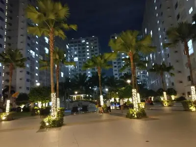 a city plaza with palm trees and lights at night at Condo MOA Complex Pasay - Shore 1 Tower C2 Residence - Home away from Home in Manila