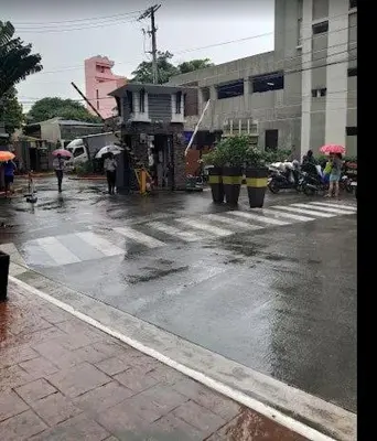 a wet city street with people walking on the street at Casa Tolentino Manila in Manila