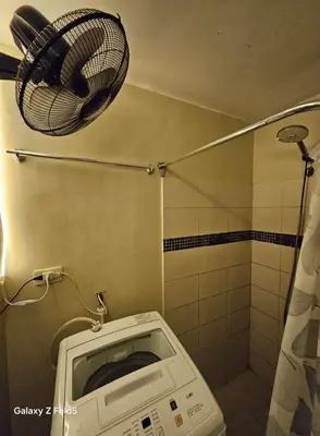 a bathroom with a shower with a fan and a toilet at Casa Tolentino Manila in Manila