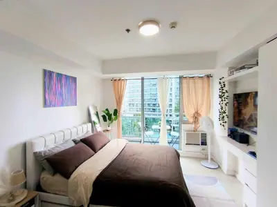 a bedroom with a bed and a large window at Masie Beach Staycation in Manila