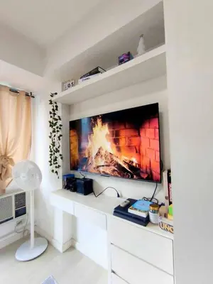 a living room with a tv with a fire on the screen at Masie Beach Staycation in Manila