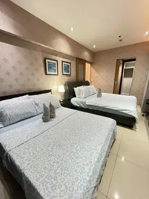 a hotel room with two beds with white sheets at MOA Shell Residences Staycation in Manila