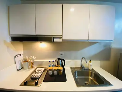 a kitchen with white cabinets and a sink at Tropical Chic Escape With City lights View- Modern Scandi in Manila