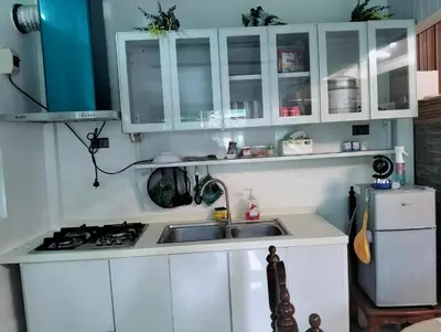 a kitchen with white cabinets and a sink and a refrigerator at Delia Secret Garden in Silang