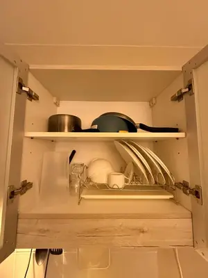 a kitchen with a shelf with dishes and pans at Monarch Parksuites 1BR with balcony in Manila