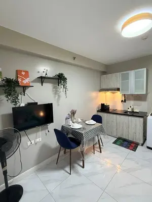a living room with a table and chairs and a kitchen at Monarch Parksuites 1BR with balcony in Manila