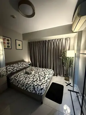 a bedroom with a bed and a window with curtains at Monarch Parksuites 1BR with balcony in Manila