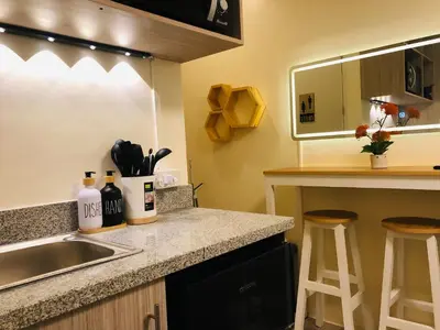 a kitchen with a sink and a counter with stools at Dos Staycation Urban Deca Cubao in Manila