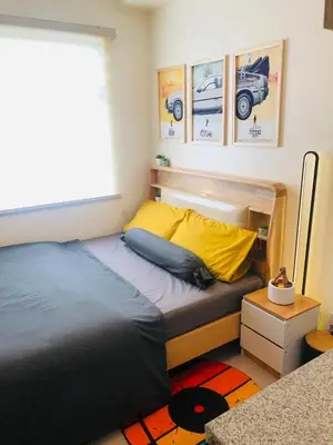 a bedroom with a bed and a window and some pictures at Dos Staycation Urban Deca Cubao in Manila