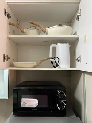 a kitchen with a microwave and some bowls and pans at Singapore Theme Sunshine 100 Tower 3 Pioneer Free Pool Gym Internet Netflix in Manila