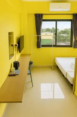 a yellow room with a bed and a desk and a window at T1 Stay Manila-Near NAIA Manila Airport and PITX in Manila