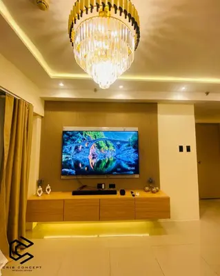 a living room with a large television and a chandelier at Serenity Suite Smart Condo 2 BR Balcony in Manila