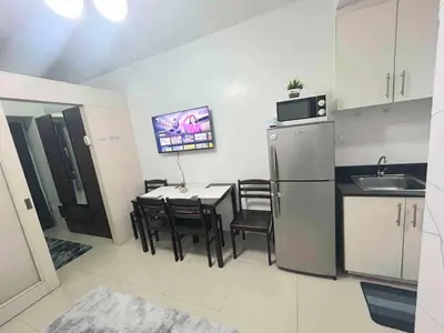 a kitchen and dining room with a table and a refrigerator at Sea Affordable staycation in Manila
