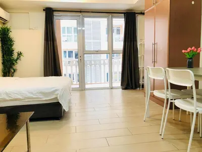 a bedroom with a bed and a table and chairs at Charming 1BR with Balcony near Venice mall&BGC in Manila