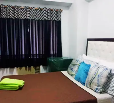 a room with a bed and a couch and a window at Althea's Homestay at Forebeswood Height in Manila
