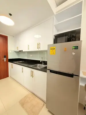 a kitchen with a refrigerator and a sink at Shell Residences Mall of Asia Caitlin's Place in Manila
