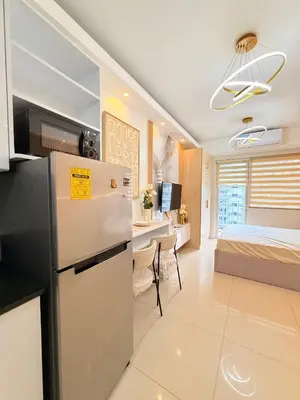a kitchen and living room with a refrigerator and a bed at Shell Residences Mall of Asia Caitlin's Place in Manila