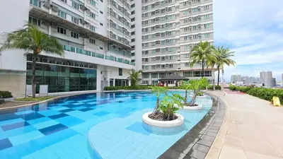 a large swimming pool with palm trees and a building at Cosy Makati Penthouse Studio with Great View in Manila