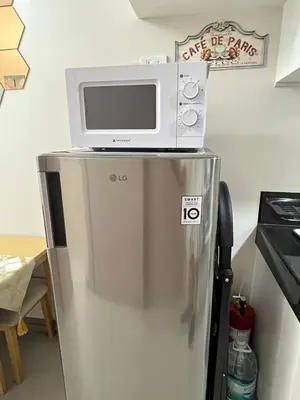 a microwave on top of a refrigerator in a kitchen at Paris Theme Near Ayala Feliz Mall 2BR Netflix Internet with Pool Parking Fee in Manila