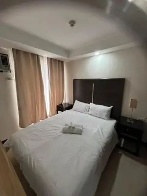 a bedroom with a large white bed with a tray on it at A Venue Residences 80G in Manila