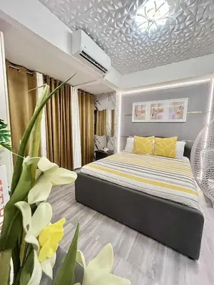 a bedroom with a bed with a yellow and white comforter at Urban Retreat at Azure in Manila