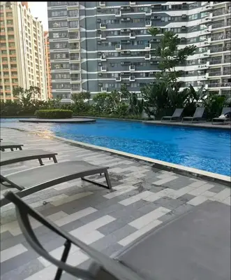a swimming pool with two chairs and a building at Pleasant Air Residences City View in Sampong