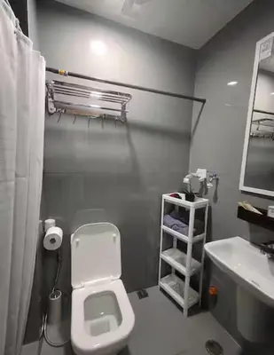 a bathroom with a white toilet and a sink at Pleasant Air Residences City View in Sampong