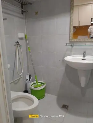 a bathroom with a toilet and a sink with a mop at Kaoru Properties in Manila