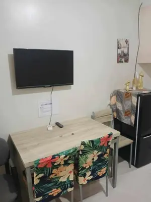 a room with a table with a television on a wall at Pasay Staycation across MOA in Manila