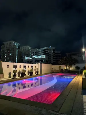 a swimming pool at night with a city in the background at Stamford Studio Condo in McKinley Hill, BGC Taguig in Manila