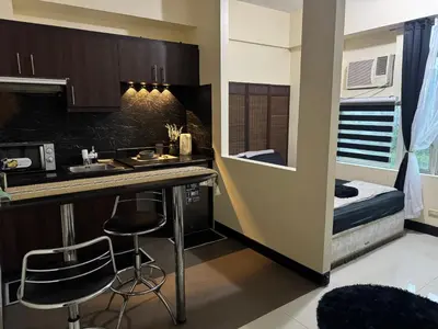 a small kitchen with a sink and a bed at Stamford Studio Condo in McKinley Hill, BGC Taguig in Manila