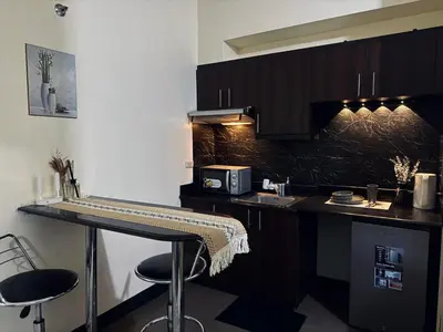 a kitchen with a counter with stools and a microwave at Stamford Studio Condo in McKinley Hill, BGC Taguig in Manila