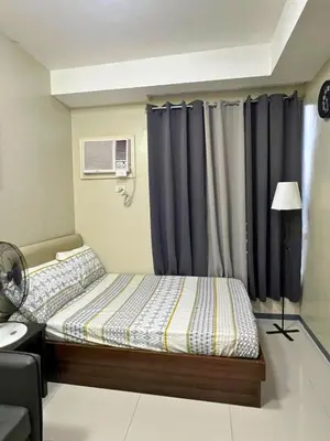 a bedroom with a bed with blue curtains at City Comfort Studio at Sunshine 100 in Manila