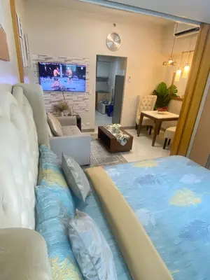 a living room with a large bed and a tv at La Rosa Home - Uptown BGC in Manila