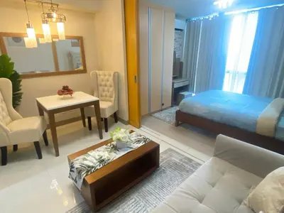 a living room with a bed and a couch and a table at La Rosa Home - Uptown BGC in Manila