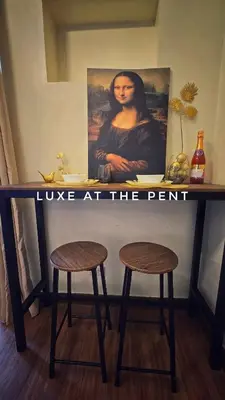 a table with two stools and a painting on the wall at The Luxe at The Pent in Manila