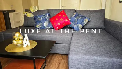 a grey couch with red and blue pillows and a table at The Luxe at The Pent in Manila