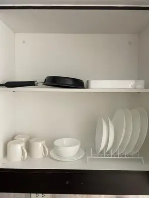 a white shelf with plates and cups and bowls at Kasara Staycation Pasig in Manila