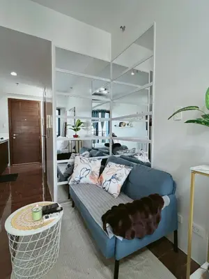 a dog laying on a blue couch in a room at Pleasant Air Residences With Balcony and Fast Wi-Fi in Manila