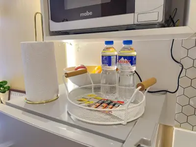 a refrigerator shelf with bottles of water and a basket at 1BR Makati, Air Residences M010 in Manila
