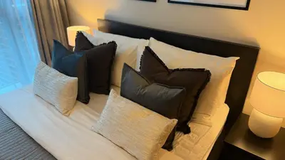 a bed with several pillows on top of it at Luxe and Modern 1BR Unit in BGC in Manila