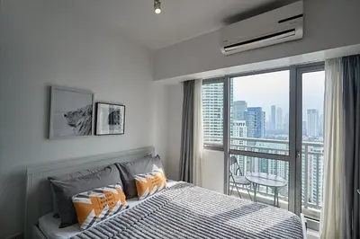 a bedroom with a bed and a large window at Cozy Crib at Acqua Residences - Rockwell Views in Manila